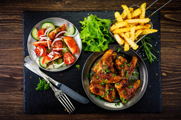 Roast chicken wings with french fries and vegetable salad 