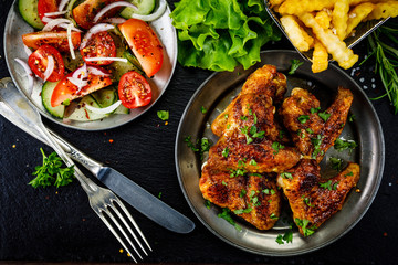 Roast chicken wings with french fries and vegetable salad 