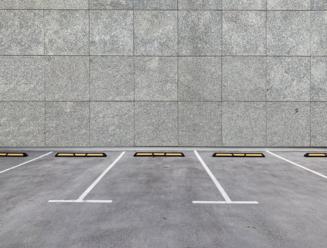 Parking spaces along building wall. Empty parking lot. 