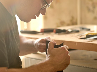 luthier is working on the neck of a classical guitar.