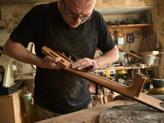 luthier is working on the neck of a classical guitar.