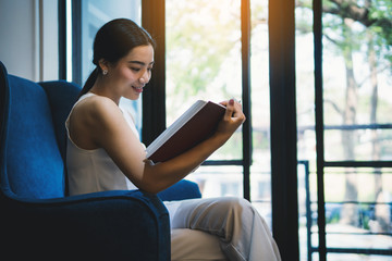 Smiling of young woman reading book at a book library.