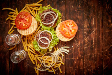 Two tasty grilled home made burgers with beef, tomato, onion and lettuce. French frides on side. Top view with copy space