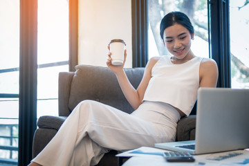 young business woman working at a coffee shop with a laptop. She drinking a coffee and use digital computer.
