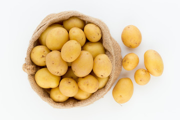 Sack of fresh raw potatoes on wooden background, top view