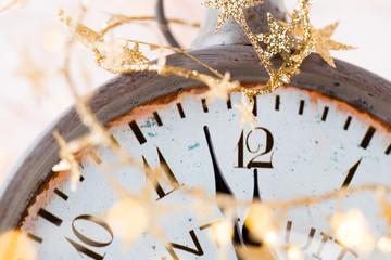 vintage alarm clock is showing midnight. It is twelve o'clock, christmas and bokeh, holiday happy new year festive concept on light bokeh background