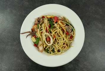Spaghetti seafood in a white dish on a black stone floor table.Top view with copy space.