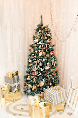 Luxury new year decor. Beige, light pink, golden, silver Christmas tree decoration. Merry Christmas and Happy Holidays! Bright lights and white interior.