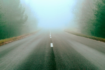 Fototapeta premium road markings and lines. Mist covers part of the road. traveling far for long distances. Highway in a natural landscape.