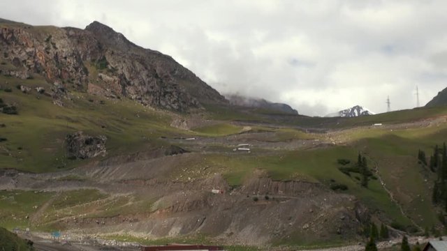 Mountain Road Through the Sujuk Pass in Kyrgyzstan With Dramatic Clouds, Rugged Peaks, and a Remote Dirt Path Winding Through High-Altitude Landscapes in Central Asia