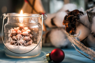 Burning Christmas candle in the form of a cone in a transparent glass on the background of New...