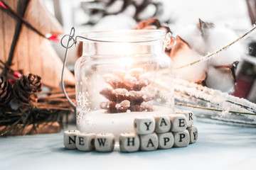 Christmas background - a burning candle in the form of Christmas trees, cones, toys and the inscription from white cubes with black letters 