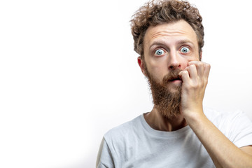 Portrait of a frustrated attractive blonde man in despair after a big collapse in his life, keeps fingers near mouth dressed casually, staring at camera with horror, isolated over white background. - obrazy, fototapety, plakaty