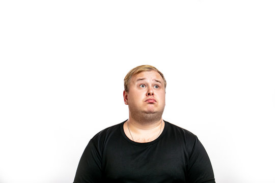 Big Fat Stout Blonde Man Dressed In Black T- Shirt Looking Up With Surprised Expression, Human Emotions Concept. Isolated On White Background With Copyspace.