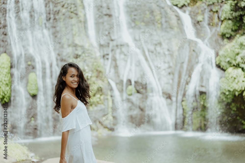 Wall mural stylish young woman taking picture for social media in waterfall