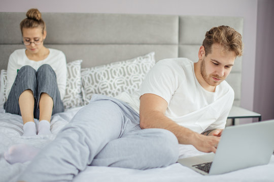 handsome fair-haired man surfing the Net while his wife reading e-book. technology concept. modern family. online cominication. non-vebal communication. virtual world