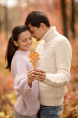 Couple in love with autumn leaf hugging in park.