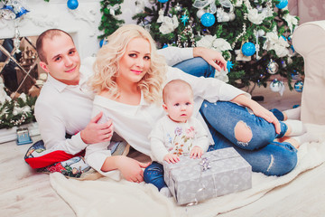 Christmas family smiling near the Xmas tree. Living room decorated by Christmas tree and present gift box. New Year theme. Toning