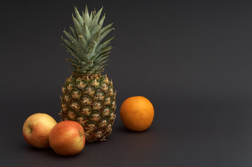 pineapple, apple, orange on black background