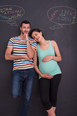 pregnant couple writing on a black chalkboard