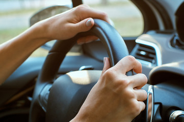 women's hands on the wheel with the phone