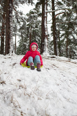 Kid sliding with sledge in the snow