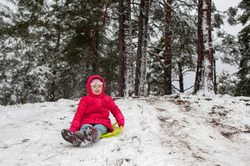 Fototapeta na wymiar Kid sliding with sledge in the snow