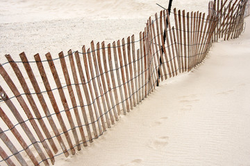 tilted weathered old wooden fence on beach sand