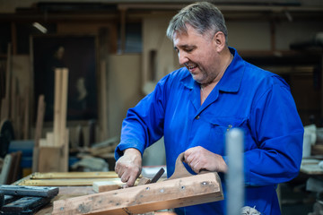 carpenter man repairs the plane with a wooden hammer in the workshop