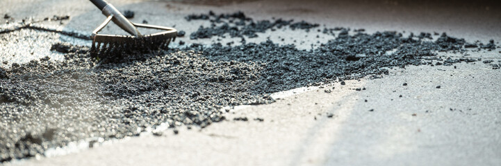 Wide view image of rakes arranging fresh asphalt mixture