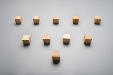 Ten blank wooden cubes placed over grey background