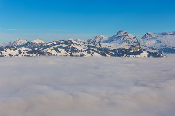 Summits of the Alps rising from sea of fog - a wintertime view from the Fronalpstock mountain in the Swiss canton of Schwyz