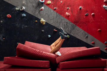 Male climber instructor practicing rock climbing on artificial wall painted in red and grey...