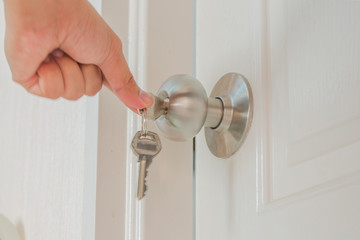 Hand hold door knob and open the white door with private key as locksmith concept.