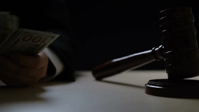 Corrupt judge counting bribe money in dark courtroom, corruption in courts. Dirty judge counting dollars