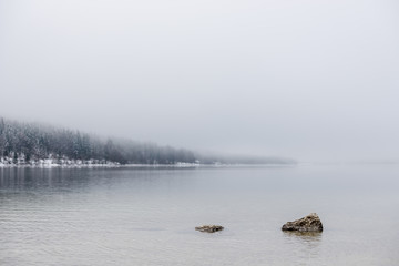 Obraz na płótnie Canvas Two rocks peeking out calm winter lake