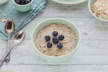 Oatmeal porridge bowl on the white wooden background.