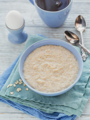 Oatmeal porridge bowl on the white wooden background.