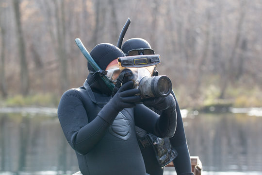 Two fishermen in wetsuit looking to photo camera in hands