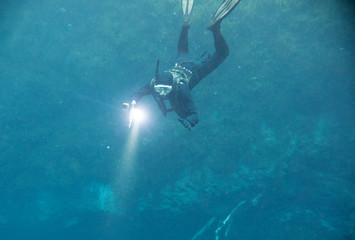 Fototapeta premium Spearfishing man with flashlight in deep of lake