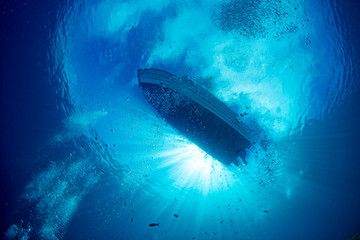 boat ship from underwater blue ocean with sun rays