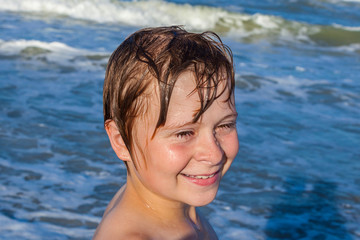 young boy enjoys the waves of the blue sea