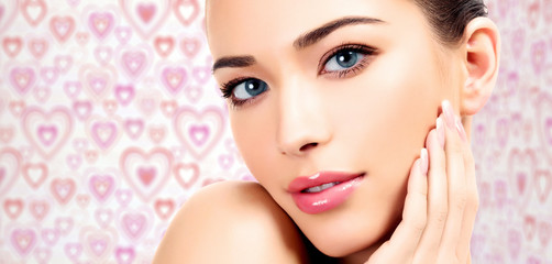 Closeup shot of beautiful female face and hand with manicured fingers, background with pink and red...