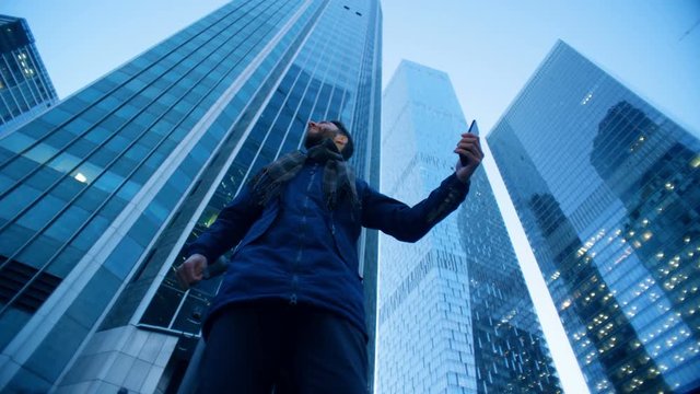 Man glancing around skyscrapers making a videocall. Epic cinema camera shot.