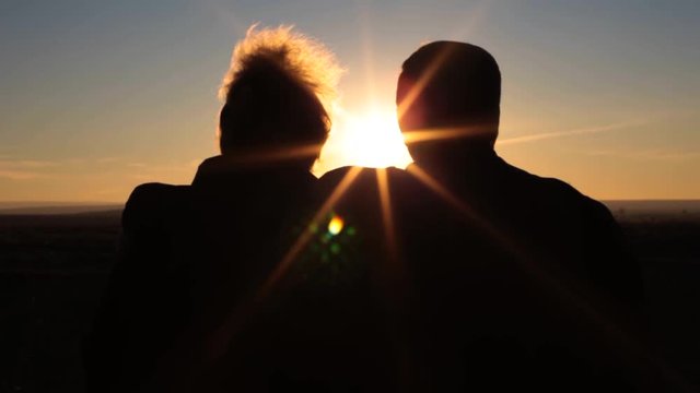 Elderly Couple Looks At The Sunset. Man Hugs A Woman