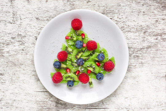 Funny edible christmas tree made from fruits and berries. Christmas breakfast idea for kids