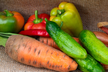 vegetables peppers, carrots and onions on burlap background