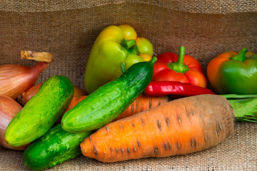 vegetables peppers, carrots and onions on burlap background