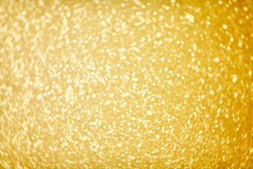 Golden sparkle glitters with bokeh effect and selectieve focus. Festive background with bright gold lights. Christmas mood concept. Copy space, close up, texture, top view.