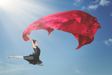 Ballerina dancing with a red fabric in the sky